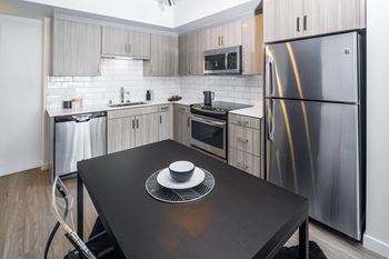 A kitchen with stainless steel appliances and a black table